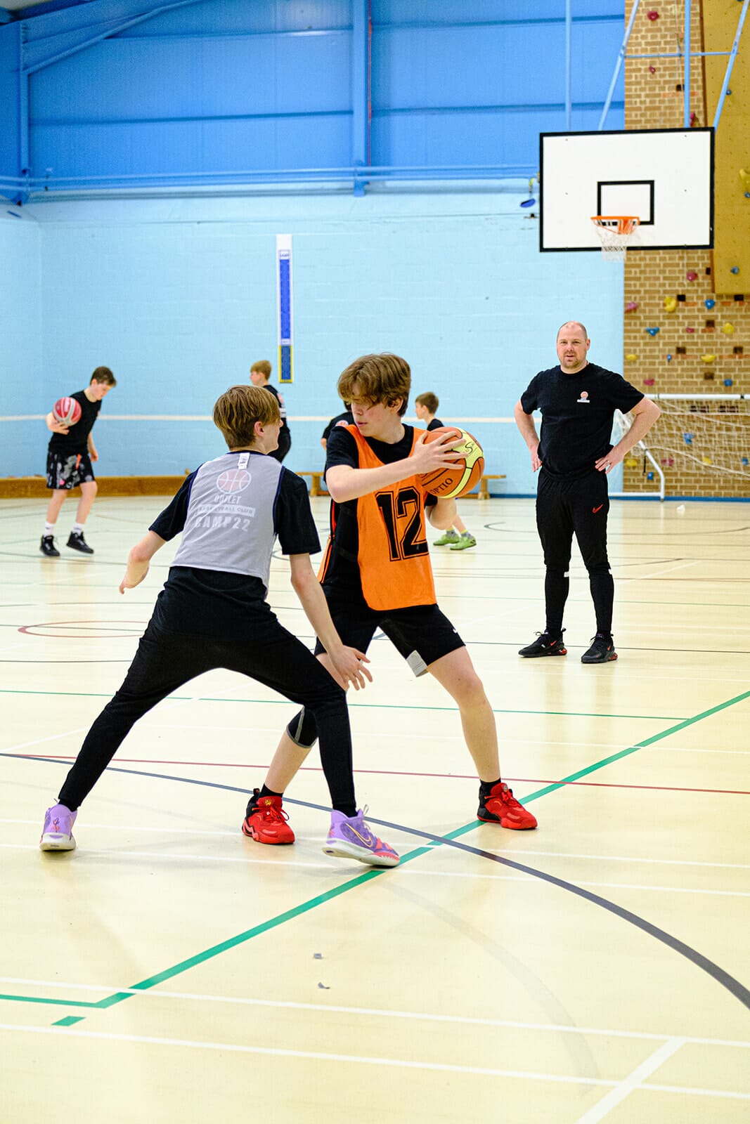 Alt: Kids participating in a Spond Club-organized basketball school holiday camps session. Title: Spond Club's Impact on Basketball School Holiday Camps Caption: Young enthusiasts at Outlet Basketball Kids Club's school holiday camps, perfecting their basketball skills, all under the efficient management of Spond Club's Courses and Academies feature. Description: An energetic image of children dressed in basketball jerseys, immersed in dribbling and shooting drills during a session at Outlet Basketball Kids Club's school holiday camps. The scene, marked by spirited players and organized play, exemplifies the operational excellence brought to such camps by the Spond Club platform.