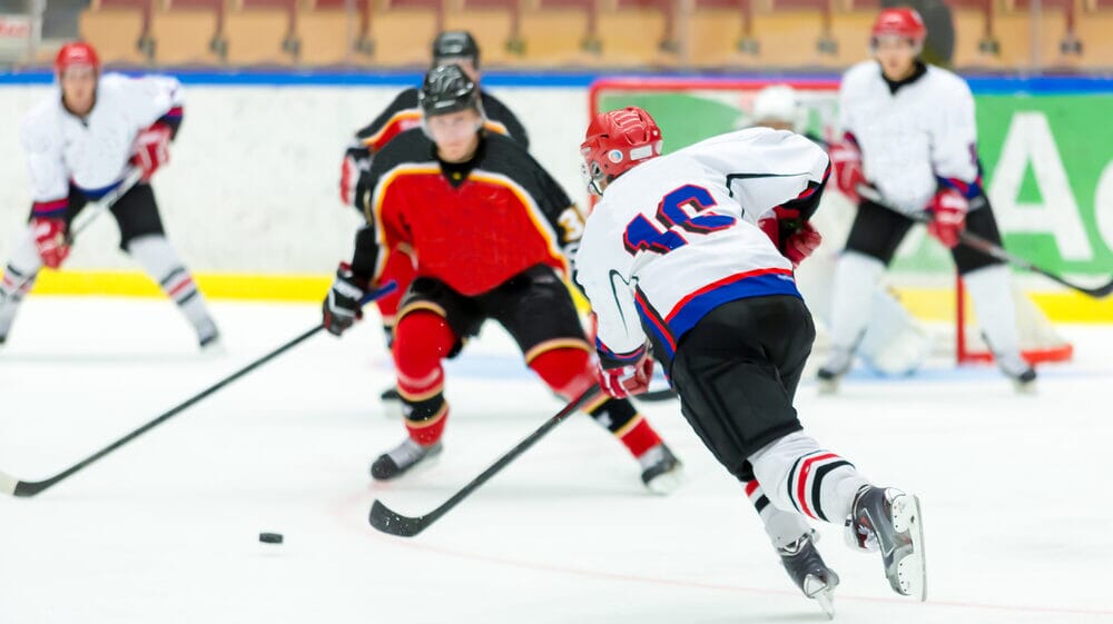 A fast-paced NHL ice hockey game, with players skating towards the puck, a prime example of one of the most popular sports in northern states.