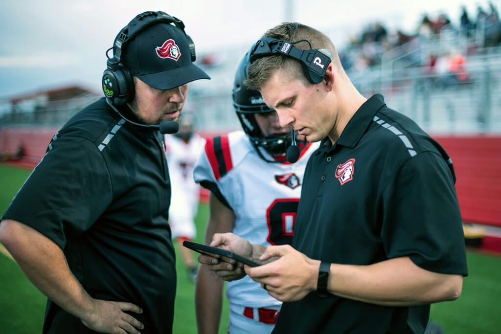 Football coach simplifying member registration by adding new team members using the Spond app.