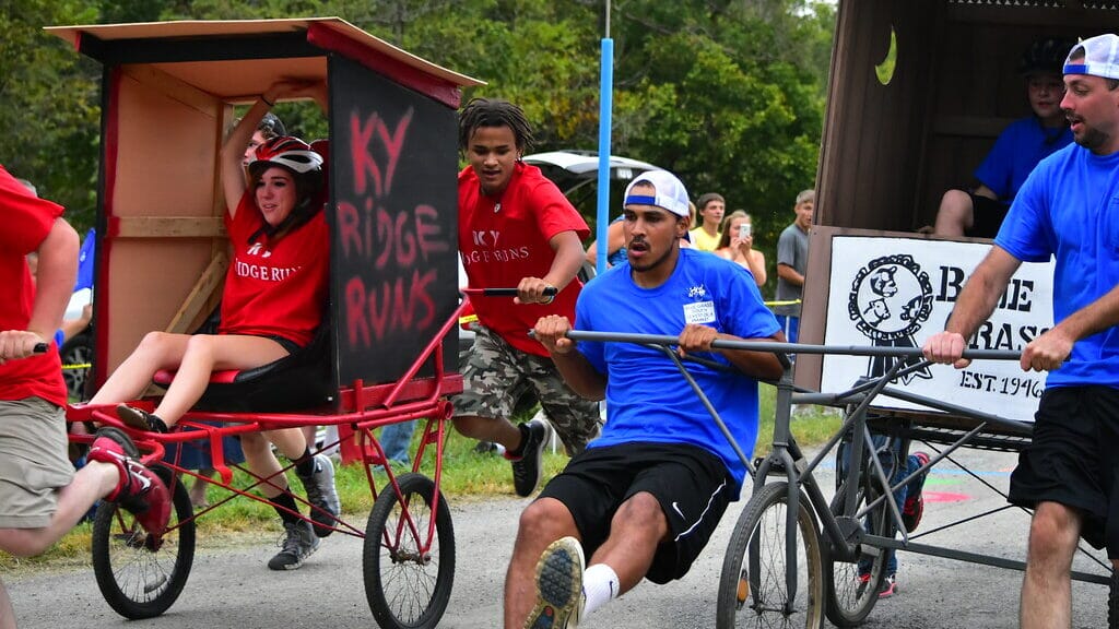 Teams racing outhouses on wheels down a track, competing in outhouse racing, one of the strangest sports in the USA.