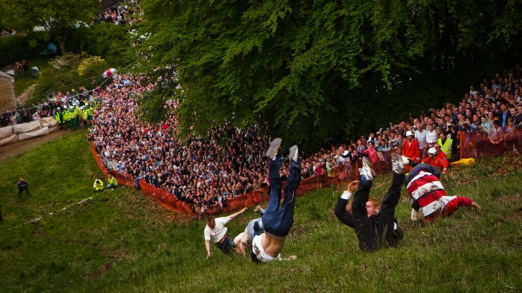 Participants chasing a wheel of cheese down Cooper's Hill during the annual cheese rolling event in Gloucestershire.