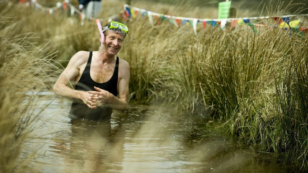 Competitor snorkelling through a water-filled bog trench in the World Bog Snorkelling Championship in Wales.