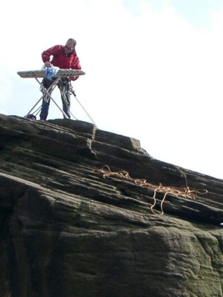 A participant ironing clothes on top of a mountain, showcasing extreme ironing, one of the strangest sports in the USA.