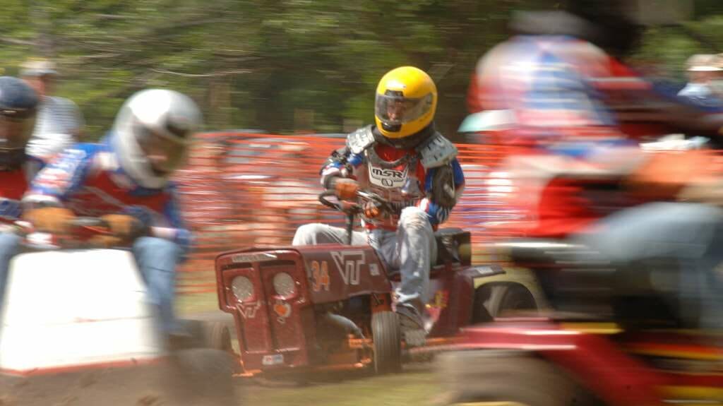 Participants racing modified lawn mowers on a track, engaging in lawn mower racing, one of the strangest sports in the USA.