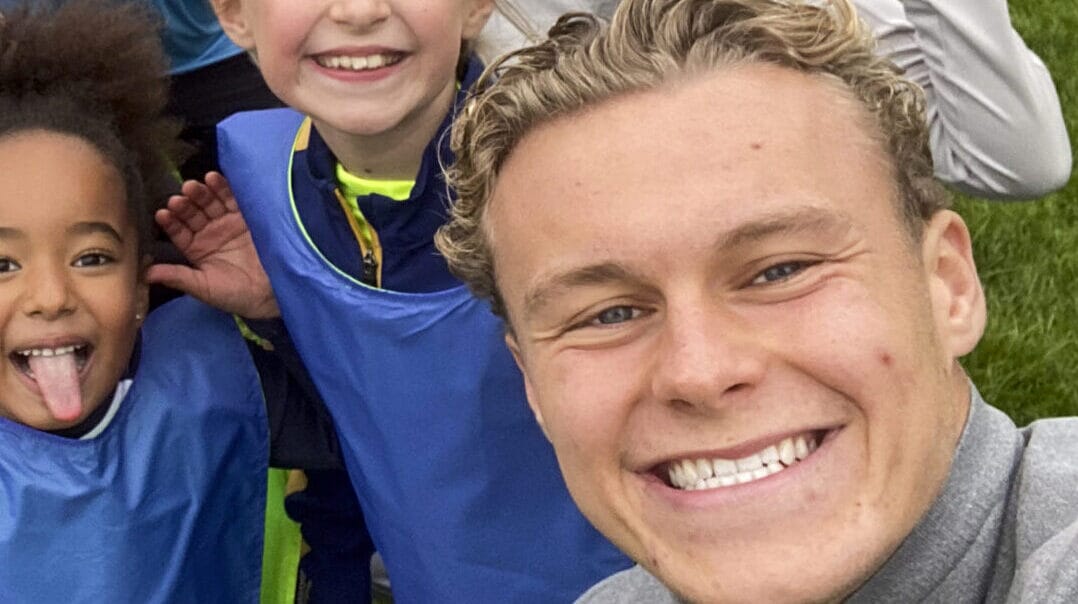 A grassroots sports coach enthusiastically leading a youth football team during practice, symbolising passion for the sport.