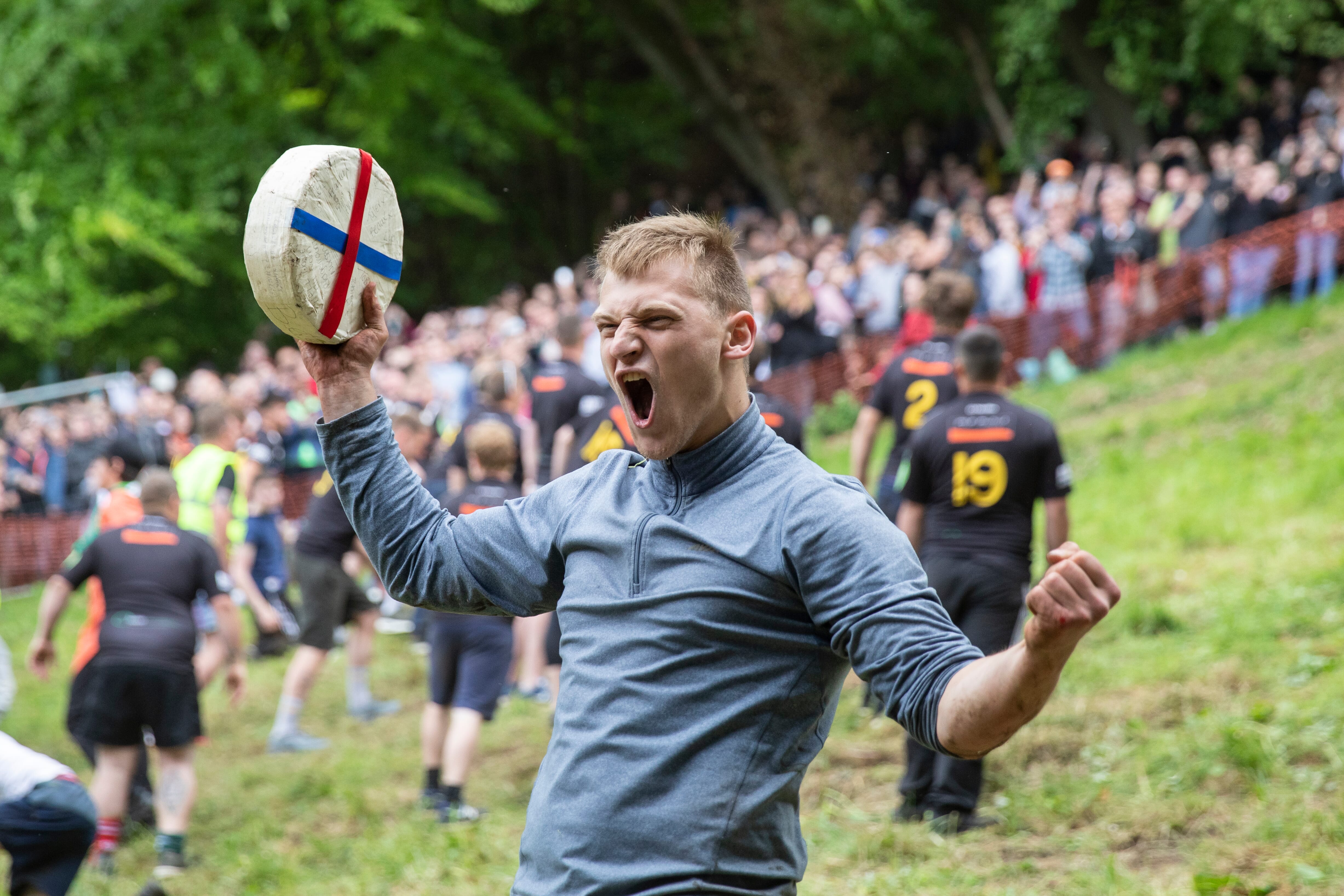 Competitors tumbling down a steep hill in Gloucestershire as they chase a rolling cheese, a quirky festive sporting tradition.