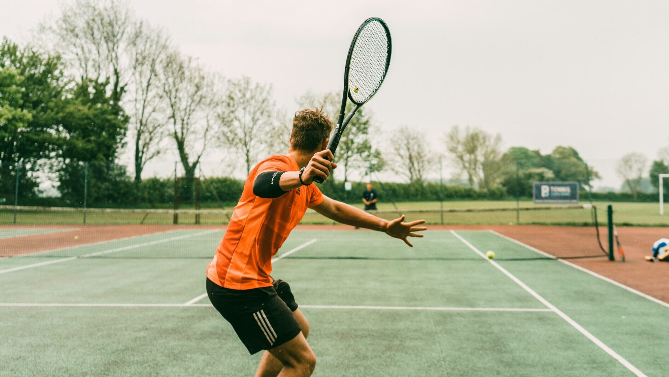 Tennis player serving the ball on a grass court during a match, exemplifying one of the biggest sports in the world.